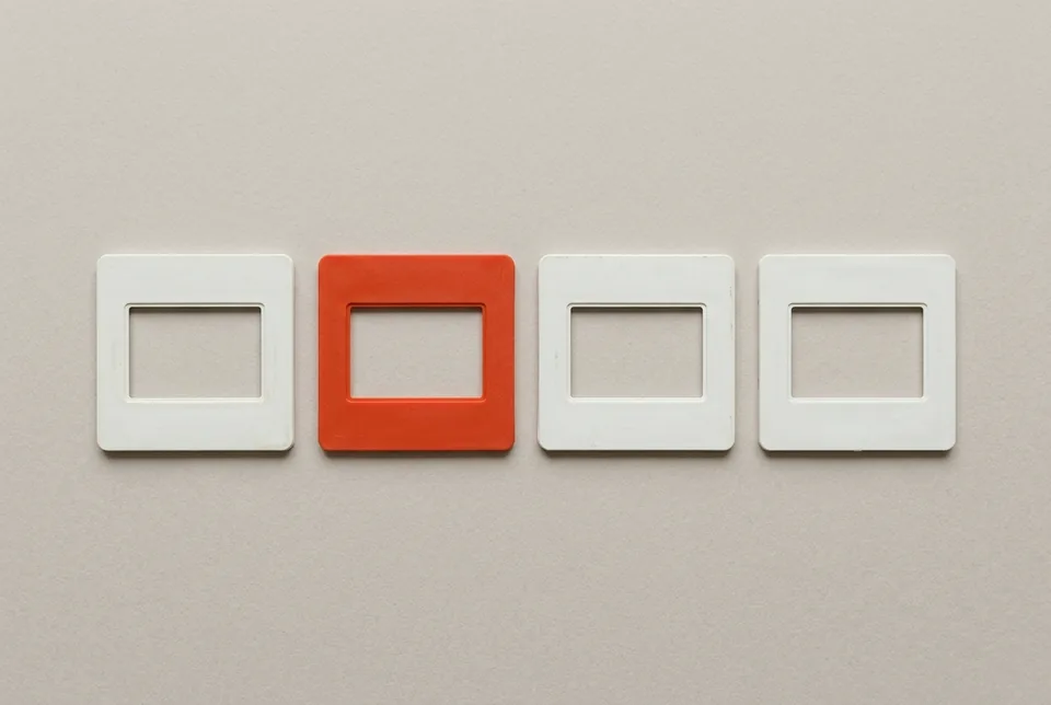 A row of four empty slide mounts, the second one orange-red